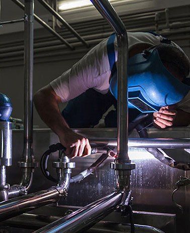 Ein Mann mit Schweißermaske schweißt ein Metallrohr an